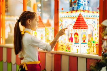 Little girl watching on showcase with handmade sugar caramel buildings. Sweet fantasy in candy store