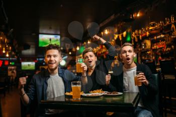 Three young men celebrates game victory in a sport bar, happy friendship of football fans