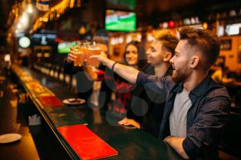 Happy football fans raised their glasses with beer at the bar counter in a sport pub, victory celebration