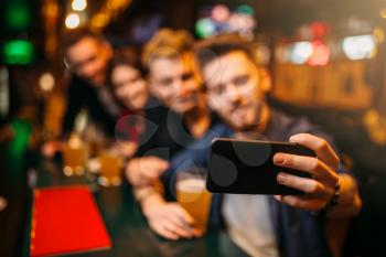 Happy football fans makes selfie on phone camera at the bar counter in a sport pub