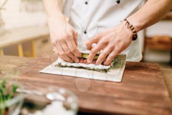 Male cook making seafood on wooden table, asian kitchen preparation process. Traditional japanese cuisine, sushi ingredients