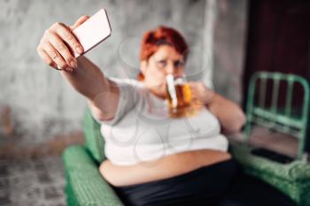Overweight woman drinks beer and makes selfie, laziness and obesity. Unhealthy lifestyle, fatty female