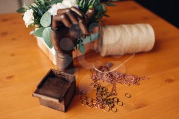 Needlework accessories, little metal rings and decorative wooden hand on the table, closeup. Handmade jewelry, bijouterie making