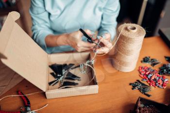 Female master with scissors makes handmade earring. Needlework, bijouterie making process