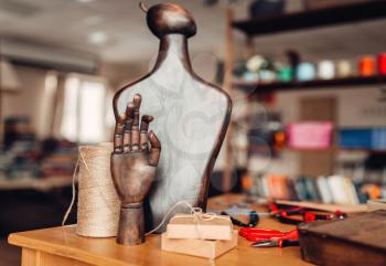 Needlework accessories, wooden hand and mannequin on the table, closeup. Handmade jewelry, workshop interior