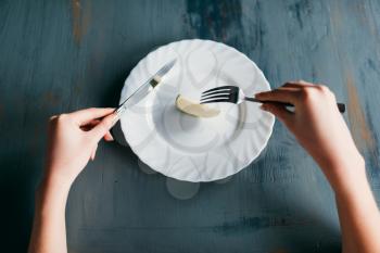 Female person against plate with a slice of apple. Weight loss diet concept