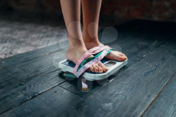 Womans feet on the scales tied with measuring tape. Fat or calories burning concept. Weight loss, hard dieting