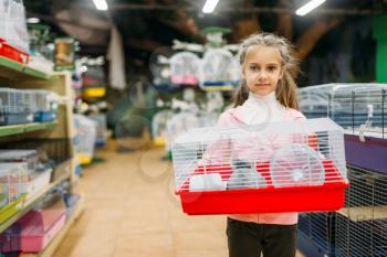Happy little girl holds cage for hamster in pet shop. Petshop advertising concept