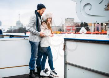 Love couple prepares to skate on the rink. Winter skating on open air, active leisure, ice-skating