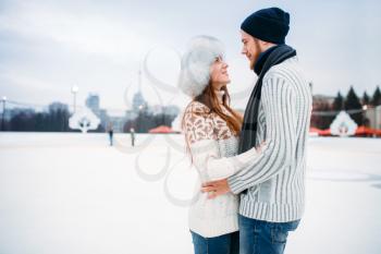 Love couple hugs on skate rink. Winter skating on open air, active leisure, ice-skating, man and woman happy together