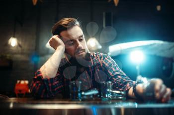Sad man sitting at the bar counter, alcohol addiction. Male person in pub, alcoholism