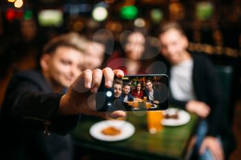 Fun friends makes selfie on phone camera in a sport bar, happy leisure of football fans