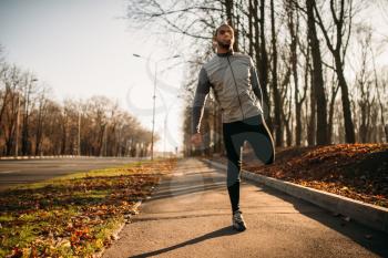 Male athlete doing exercise on workout outdoors. Runner in sportswear on training in park