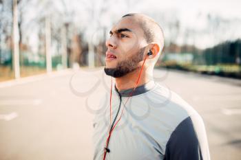 Athlete in headphones before jogging in park. Jogger on morning fitness workout. Runner in sportswear, fitness training outdoor