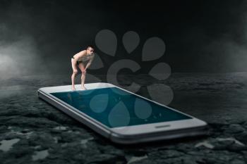 Swimmer ready to dive into the pool is made from large phone screen. Always be in touch or online addiction concept, social addicted people. Scaling effect