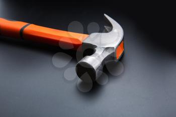 Orange hammer on dark matt background, closeup, nobody. New hummer, workshop tool