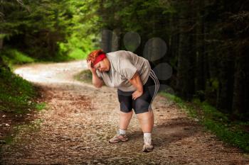 Overweight woman tired after a run in the forest. Burning of calories. Female obesity, bulimic. Unhealthy food eating