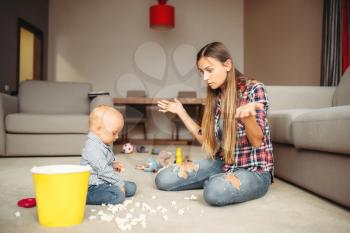 Little kid spilled popcorn on the floor, motherhood problems. Sad mom and son together at home