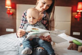 Young mother and little male child reading a book, kids education. Mom and son happy together at home, togetherness