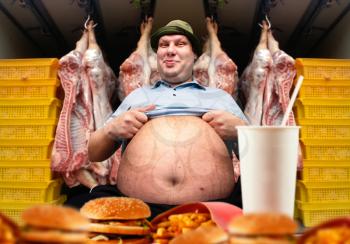 Happy fat man and fast food, pork carcasses on background. Overweight people, burgers eating