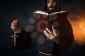 Medieval monk praying with book in hands in church, secret ritual. Mystery and spirituality