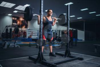 Muscular athlete prepares to make squats with barbell in gym. Weightlifting workout, powerlifting training