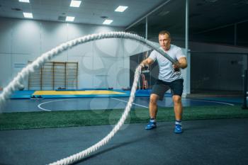 Male athlete with ropes in gym, crossfit workout. Cross fit training, strength exercise