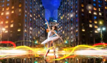 Classical ballet dancer in white dress dancing on city road, cityscape with long exposure light effect. Graceful ballerina poses in studio