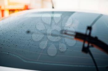 Car rear glass with drops of wax closeup, nobody, waxing process, water-repellent coating. Touchless self-service car wash outdoor. Automobile washing. Vehicle cleaning at summer day 