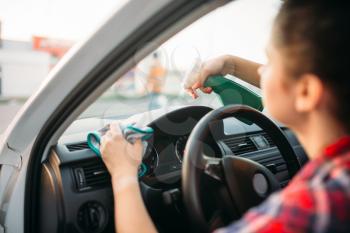 Female person polishes the dashboard of the car, polishing process on carwash. Lady on self-service automobile wash. Outdoor vehicle cleaning