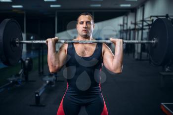 Male powerlifter preparing deadlift a barbell in gym. Weightlifting workout, lifting training, athlete works with weight in sport club