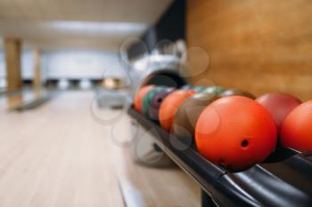 Color bowling balls in feeder, lane with pins on background, nobody. Bowl game concept