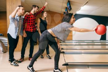 Female bowler on lane, ball throwing in action, strike shot preparation. Bowling alley teams playing the game in club, active leisure