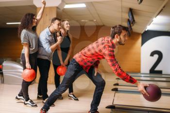 Male bowler throws ball on lane, front view, throwing in action. Bowling alley teams playing the game in club, active leisure