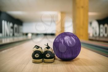 Bowling ball and house shoes on lane in club, closeup view, nobody. Bowl game concept, active hobby