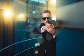 Bodyguard in suit and sunglasses with a gun in his hands. Security guard is a risky profession, professional guarding, politicians and business persons protection from the danger of life