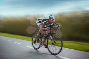 Cyclist in helmet and sportswear rides on bicycle, speed effect, side view