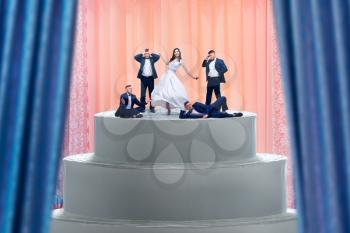 Wedding cake, bride and many grooms figurines on the top. Dummy pie for newlyweds with little figures