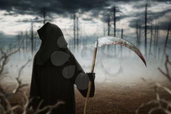 Death in a black hoodie and with a scythe in the dark misty forest. Horror style, fear, spooky demon