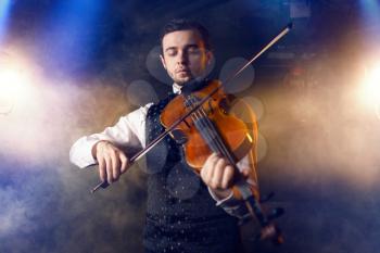 Male violinist playing classical music on violin, fiddler on the stage in action