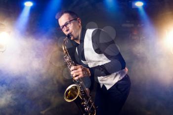 Male saxophonist playing classical music on sax. Saxophone melody performer on the stage in action