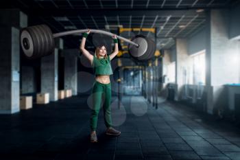 Female athlete with very big barbell on workout in gim. Woman with weights, weightlifting sport concept