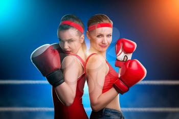 Two female boxers in red boxing gloves standing back to back. Fighting sport and martial art concept