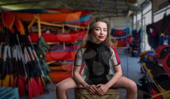 Female sportman in wetsuit, boats and diving gear on background. Boating rental or rescue station