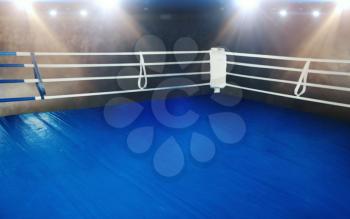 Boxing ring with blue flooring and white ropes. Professional arena for sport competitions and fighting tournaments