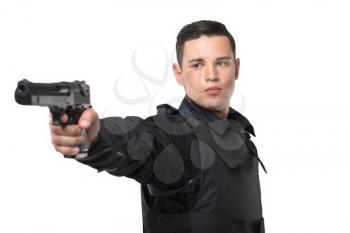 Policeman aims with a gun, black uniform with body armor, white background, front view. Cop in special ammunition