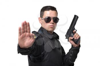 Seriuse cop in sunglasses poses with gun, black uniform with body armor, white background. Policeman in special ammunition