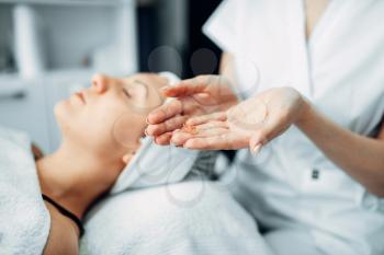 Beautician hands with cream against female patient, cosmetology clinic. Facial skincare, rejuvenation procedure in spa salon