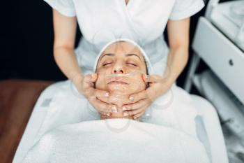 Face massage to female patient, cosmetology clinic. Facial skincare, rejuvenation procedure in spa salon
