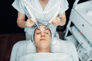Beautician makes face rejuvenation procedure to woman, cosmetology clinic. Facial skincare in spa salon, health care
